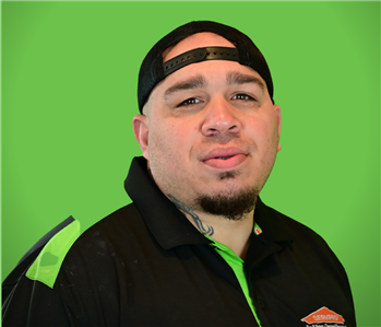 A male servpro SERVPRO smiles infront of a green background.